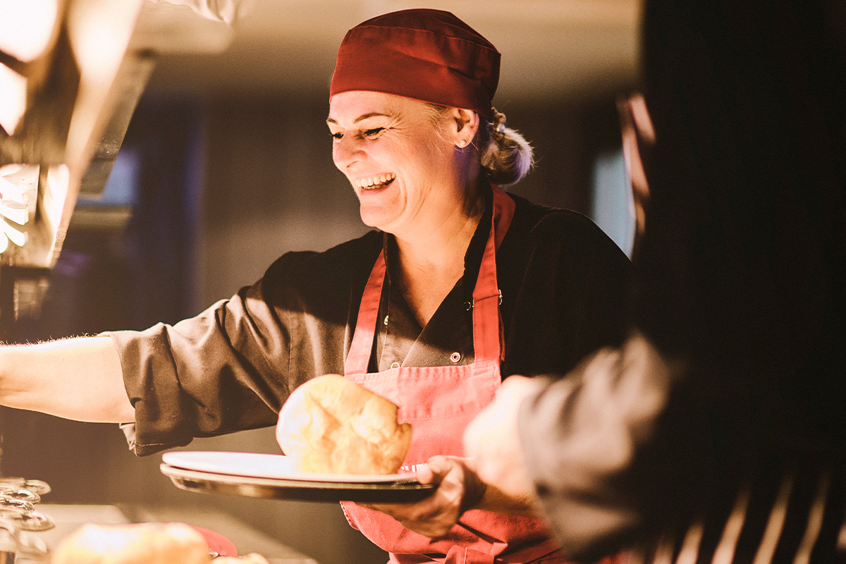Our chef is refilling the carvery station for service, while smiling and laughing with her colleague.